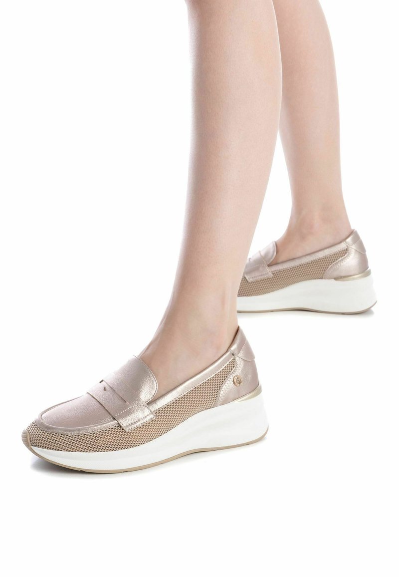 Zapatos slip-on de color rosa dorado metálico con lados de malla, suelas en cuña blancas y un diseño minimalista. Textura suave con un acabado liso.