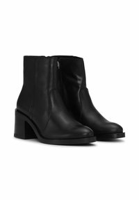 Crne kožne gležnjače zaokruženog vrha, s bočnim patentnim zatvaračem i debelom srednje visokom petom. Glatka tekstura i minimalistički dizajn.