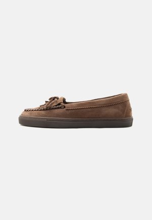 Mocassin en daim marron avec des détails cousus, nœud sur le dessus et semelle en caoutchouc foncé, vu de profil sur fond blanc.