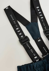 Schwarze verstellbare Hosenträger mit weißem "BAKER BY TED BAKER"-Text, die an dunklen Stoffhosen befestigt sind.
