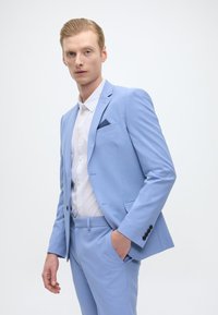 Fato azul claro com corte slim, casaco de um só botão e calças combinando. Apresenta colarinho serrado, bolso frontal e punhos com botão.