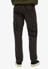Pantalon cargo marron avec poches latérales et coupe ample, fabriqué en tissu durable. Caractéristiques d'un design classique avec une couleur unie et des accents minimalistes.
