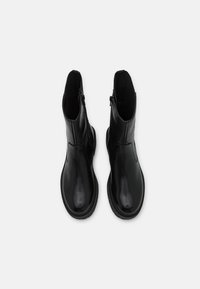 Černé kotníkové boty vyrobené z hladké kůže, mají zaoblenou špičku a boční zipy, s elegantní siluetou a minimalistickým designem.