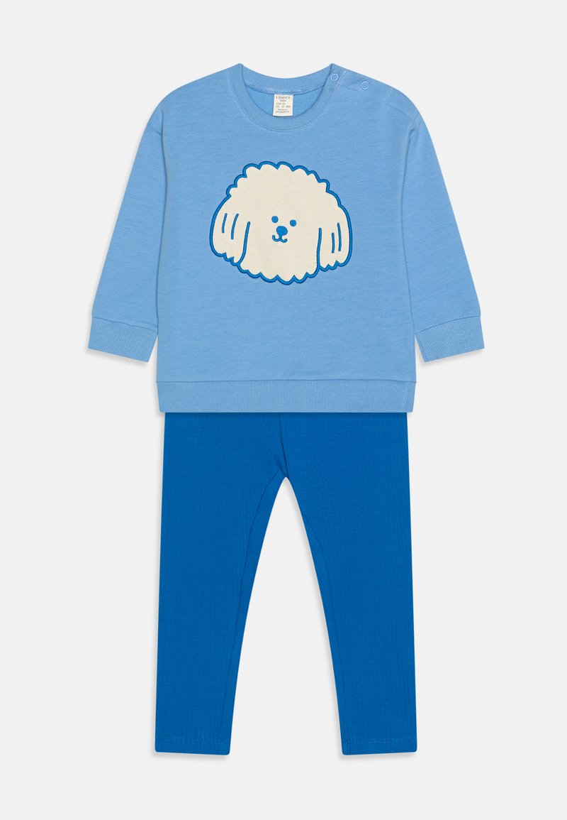 Sweatshirt bleu clair avec un graphique d'un chien blanc duveteux, associé à un legging bleu uni. Comprend un tissu doux et un ajustement confortable.