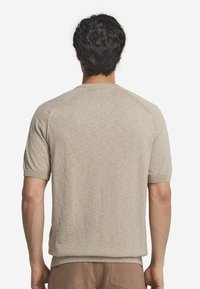 Lys beige kortærmet sweater med tekstureret overflade, rund hals, ribbede manchetter og en afslappet pasform, der har raglanærmer for nem bevægelse.