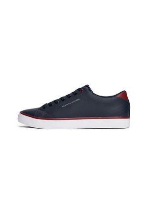 Granatowy niski tenis z białą podeszwą, czerwonymi akcentami na pięcie i górnej krawędzi podeszwy, czarnymi sznurówkami oraz logo "Tommy Hilfiger" po boku.