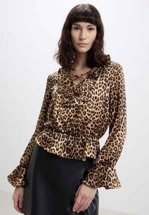 Blusa con stampa leopardata, maniche lunghe, polsini arricciati, scollatura con lacci e vita a peplo. Tessuto setoso con finitura lucida.