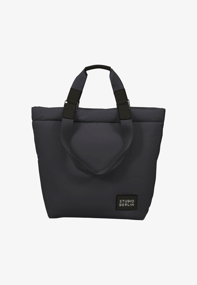Borsa a tracolla grigia con tessuto morbido e imbottito, due manici robusti e forma rettangolare. Presenta un'etichetta nera con il testo "STUDIO BERLIN".