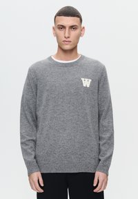 Gray knitted sweater with long sleeves, ribbed cuffs and hem, features a cream letter "W" on chest, round neckline, soft texture.