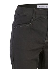 Fekete farmernadrág sima textúrával, rugalmas derékrésszel, elülső zsebekkel és kontrasztos varrási részletekkel.