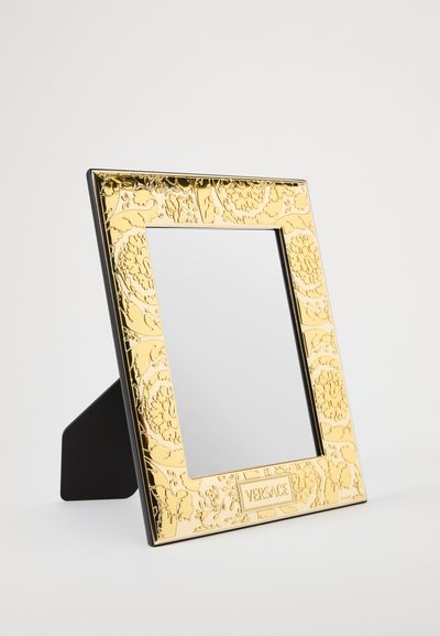 Złota ozdobna ramka na zdjęcia z wytłaczanym kwiatowym wzorem, centralnym lustrem oraz czarnym tylnym wspornikiem z logo Versace.