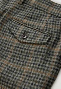 Hosen aus Wollmischung mit einem grün-braunen Hahnentrittmuster, einer Standardtasche mit brauner Knopfdetail und einer strukturierten Oberfläche.