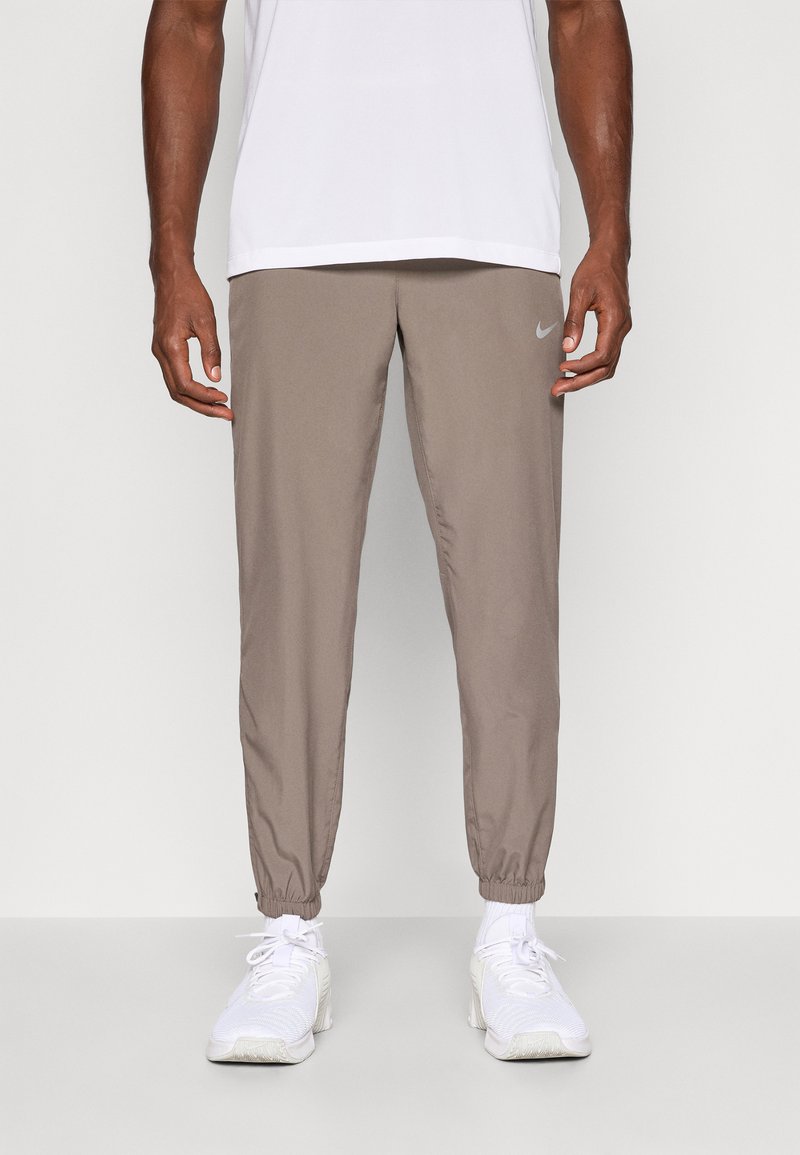 Nike joggingbukser i taupe, lavet af letvægtsstof. Har elastiske manchetter og en lille logo-detalje på venstre lår.