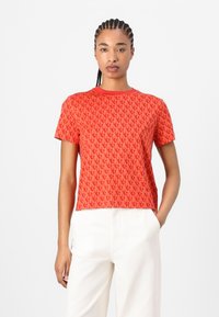Red short-sleeve t-shirt featuring an all-over pattern with a textured design. Crew neckline and relaxed fit, made from soft fabric.
