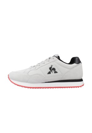 Baskets de sport en suède gris avec des accents noirs, arborant un logo, une semelle intermédiaire blanche et une semelle extérieure rouge. Comprend des lacets et un col rembourré.