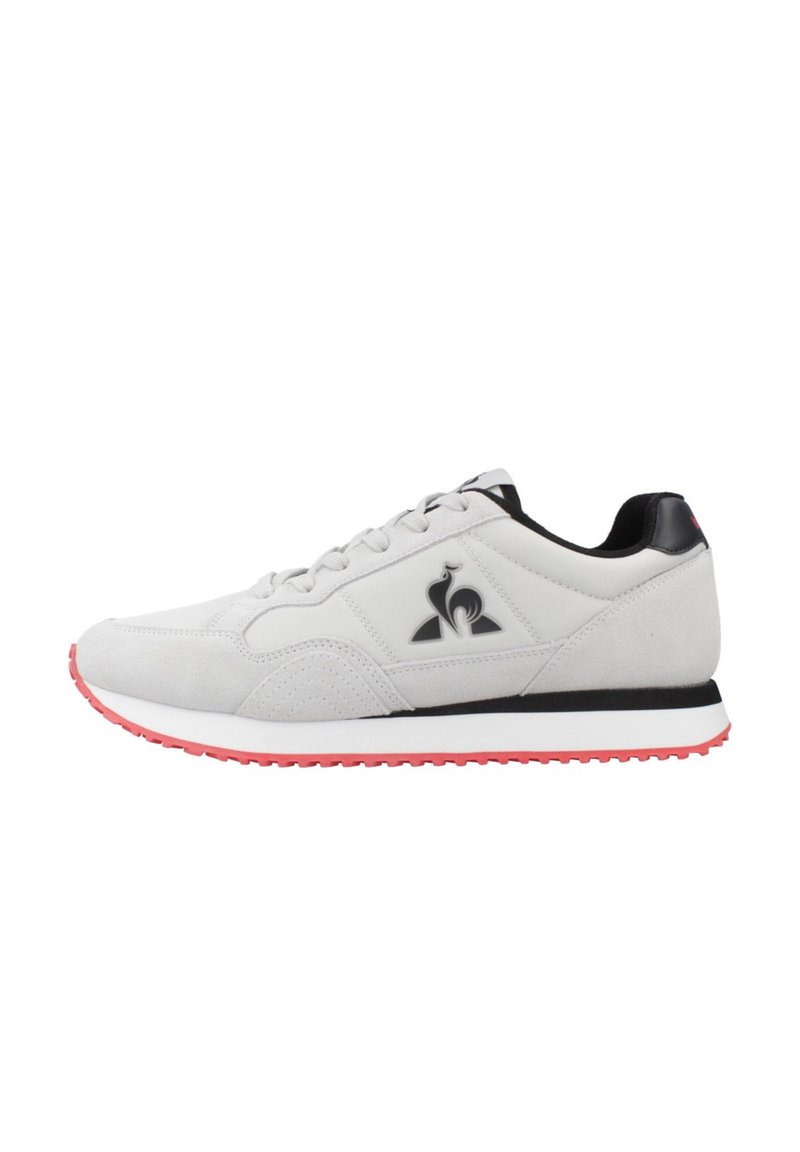 Zapatillas deportivas de ante gris con acentos negros, con un logo, una media suela blanca y una suela exterior roja. Incluyen cordones y un cuello acolchado.