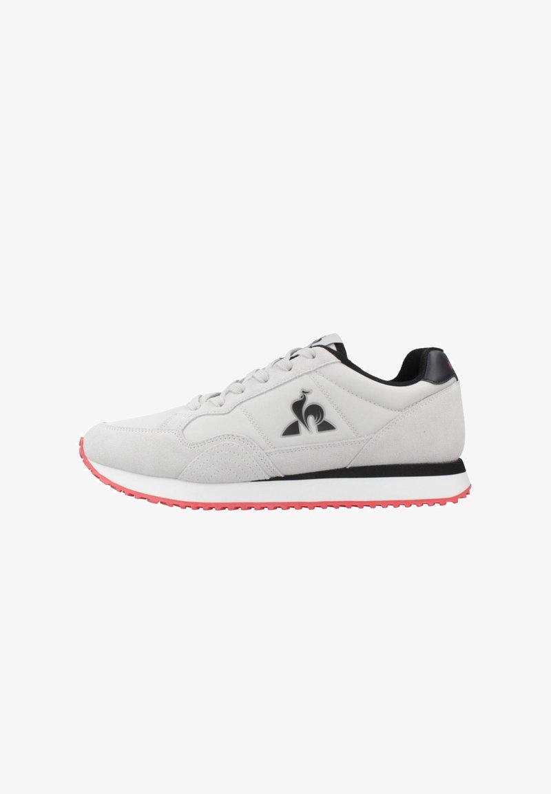 Zapatillas deportivas de ante gris con acentos negros, con un logo, una media suela blanca y una suela exterior roja. Incluyen cordones y un cuello acolchado.