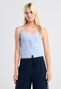 Light blue knitted camisole with scalloped edges and a front tie detail. It features thin straps and a fitted design.