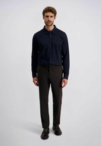 Marineblauwe overhemd met lange mouwen en een spread collar, gecombineerd met donkerbruine op maat gemaakte broeken en donkere nette schoenen. Textuurdetails van de stof zichtbaar.