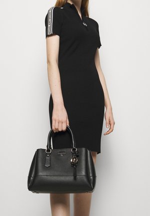 Sorte ribbede kjole med korte ærmer og lynlås. Holder en sort lædertaske med tekstureret overflade og rundt logo charms.