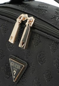 Zwarte handtas van textuurmateriaal, met gouden ritsen, een merklogo in een driehoekig accent, en heeft reliëfpatronen.
