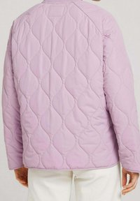 Gesteppte Jacke in hellem Lavendel mit einem Wellenmuster und glatter Textur. Das Design hat einen runden Kragen und anliegende Ärmel.