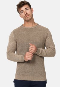 Maglione beige con un design a coste testurizzate sulla parte superiore del corpo, maniche attillate e un colletto scuro a contrasto.