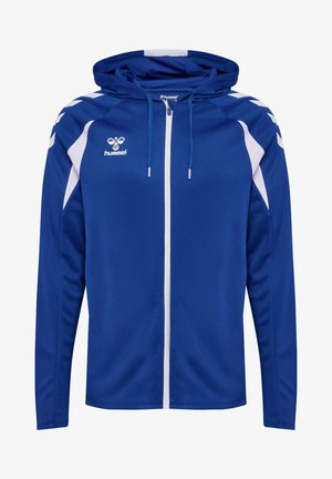 Blauwe sportjas met capuchon, witte ritssluiting, witte chevronstrepen op de schouders en hummel-logo op de borst.
