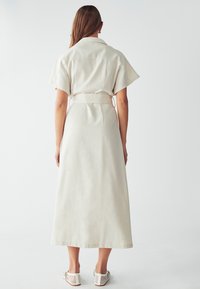 Beige linnen midi-kjole med kortærmer, bælte i taljen og lige silhuet, med en glat tekstur og minimalistisk design.