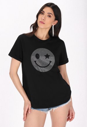 Tricou negru din bumbac, cu un design strălucitor al unei fețe zâmbitoare, însoțit de o stea și un ochi, cu mâneci scurte răsucite și croi lejer.