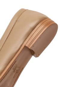 Beige leather platform shoe with a rounded toe, featuring a smooth texture, wooden detailing on the heel, and a simple design element.