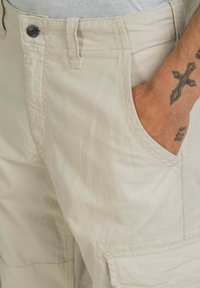 Beige cargoshorts van lichtgewicht stof, met een voorzak, een platte tailleband met een knoop en een subtiele textuur.