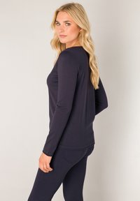 Marineblauwe longsleeve top van zacht materiaal, met een getailleerde pasvorm en ronde halslijn. Geaccentueerd met gestikte naden en een gladde textuur.
