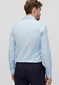 Lichtblauwe langesleeve shirt met een puntige kraag, enkele knoopmanchetten en een gladde textuur. Draag het met donkere broek. Achteraanzicht.