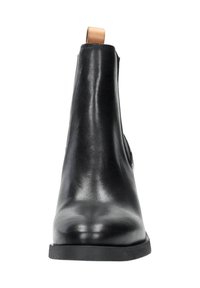 Zwarte leren enkellaars met een gladde afwerking, elastische zijkanten en een tan kleurige lus aan de achterkant; lage rubberen zool voor stabiliteit.
