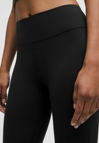 Fekete, magas derekú leggings, sima, rugalmas anyagból. Széles derékszárral és minimális varrással rendelkezik, ami áramvonalas megjelenést kölcsönöz.