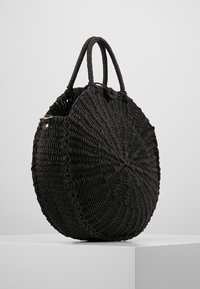 Rund svart halmväska med två stabila handtag, med en tätt vävd textur och en sömlös cirkulär design.