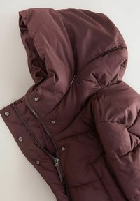 Burgundy pufferjacka med huva, med dragkedja framtill, tryckknappar och kviltad design. Slät, vattenavvisande tygstruktur.