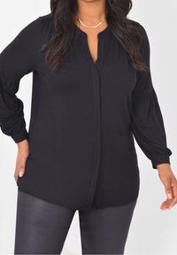 Czarna, długosleeve bluzka z wykładanym kołnierzykiem i marszczonymi rękawami. Lekki materiał o gładkiej teksturze, z zaokrąglonym dołem.