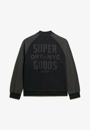 Czarna i szara kurtka bomber z prążkowanym kołnierzem i mankietami. Na plecach znajduje się wyraźny napis "SUPER DRY NYC GOODS 34TH ST".