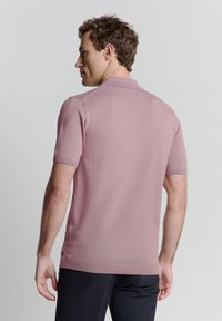 Polo shirt met korte mouwen in pastelroze, uitgevoerd in een gestructureerde breisel stof, met een klassieke kraag en een slim fit ontwerp met minimale details.
