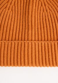 Orange geripptes Strickgewebe mit vertikalen und horizontalen Rillen, das eine detaillierte Textur und weiches Wollmaterial zeigt.