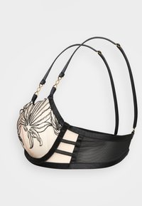 Lacy black and peach bra with floral embroidery, sheer mesh sides, adjustable straps, and gold-tone hardware accents.