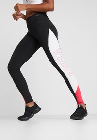 Legginsy PUMA w czarnym kolorze z białymi i różowymi akcentami, z wysokim stanem i logotypem nadrukowanym z boku w jasnoróżowym kolorze.