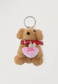 Porte-clés en peluche représentant un chien marron portant un collier rouge, tenant un cœur rose avec le texte « FUR EVER » et un petit charm en forme de nœud orné de perles.