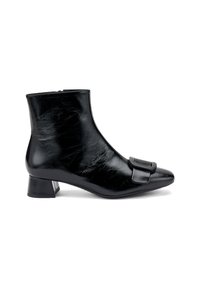 Botín negro de cuero hasta el tobillo con punta afilada, tacón bajo y cuadrado, y una gran hebilla decorativa en la parte frontal. Textura suave con un acabado brillante.