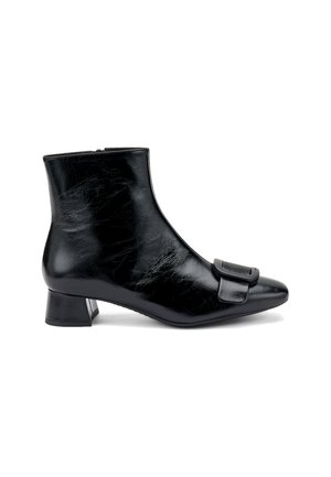 Stivale ankle in pelle nera con punta affusolata, tacco basso a blocco e una grande fibbia decorativa sulla parte frontale. Texture liscia con una finitura lucida.