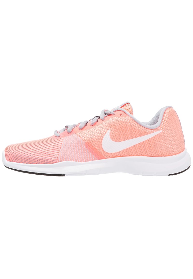 Baskets de sport rose clair avec un dessus en maille, swoosh blanc de Nike, accents gris et semelle blanche. Présente une surface texturée et un design épuré.