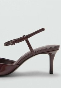 Burgundské lakované sandály na podpatku s tenkým ankletovým páskem, zaoblenou špičkou a štíhlým stiletto podpatkem s lesklým povrchem.