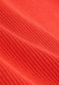 Material texturat roșu cu un model nervurat, având linii orizontale. Suprafața pare moale și ușor ridicată.